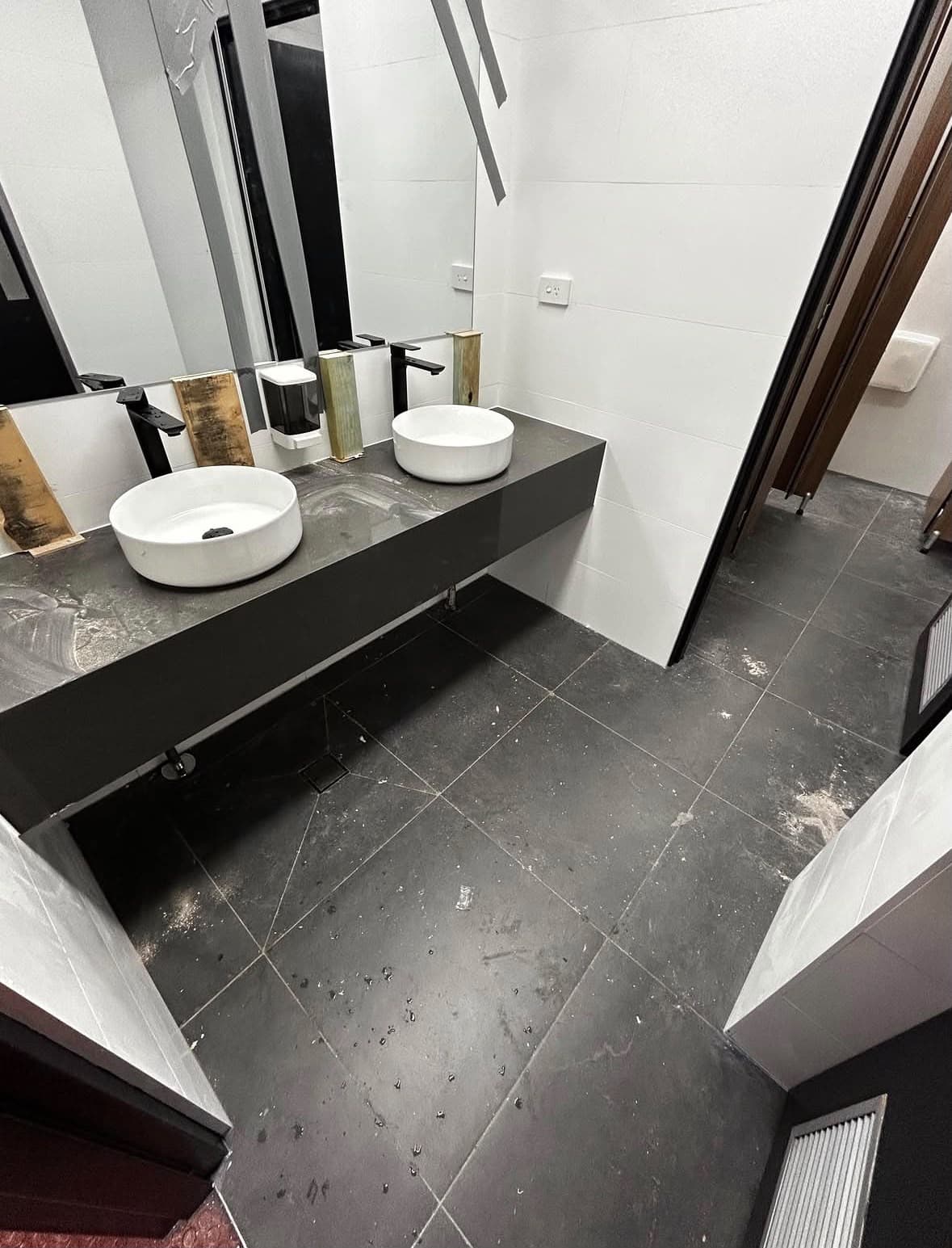 A commercial washroom before a Capital Cleaning Company clean, dusty and marked